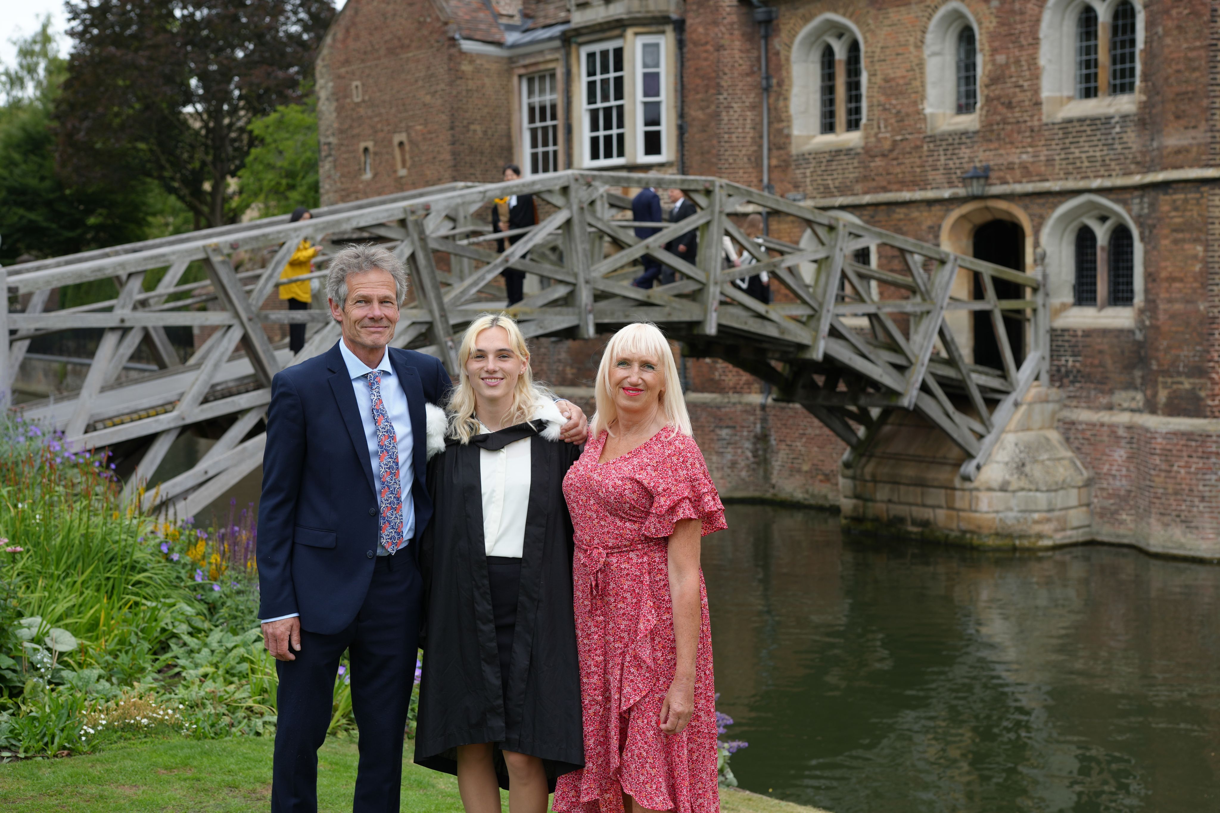 Three people pose outside by bridge