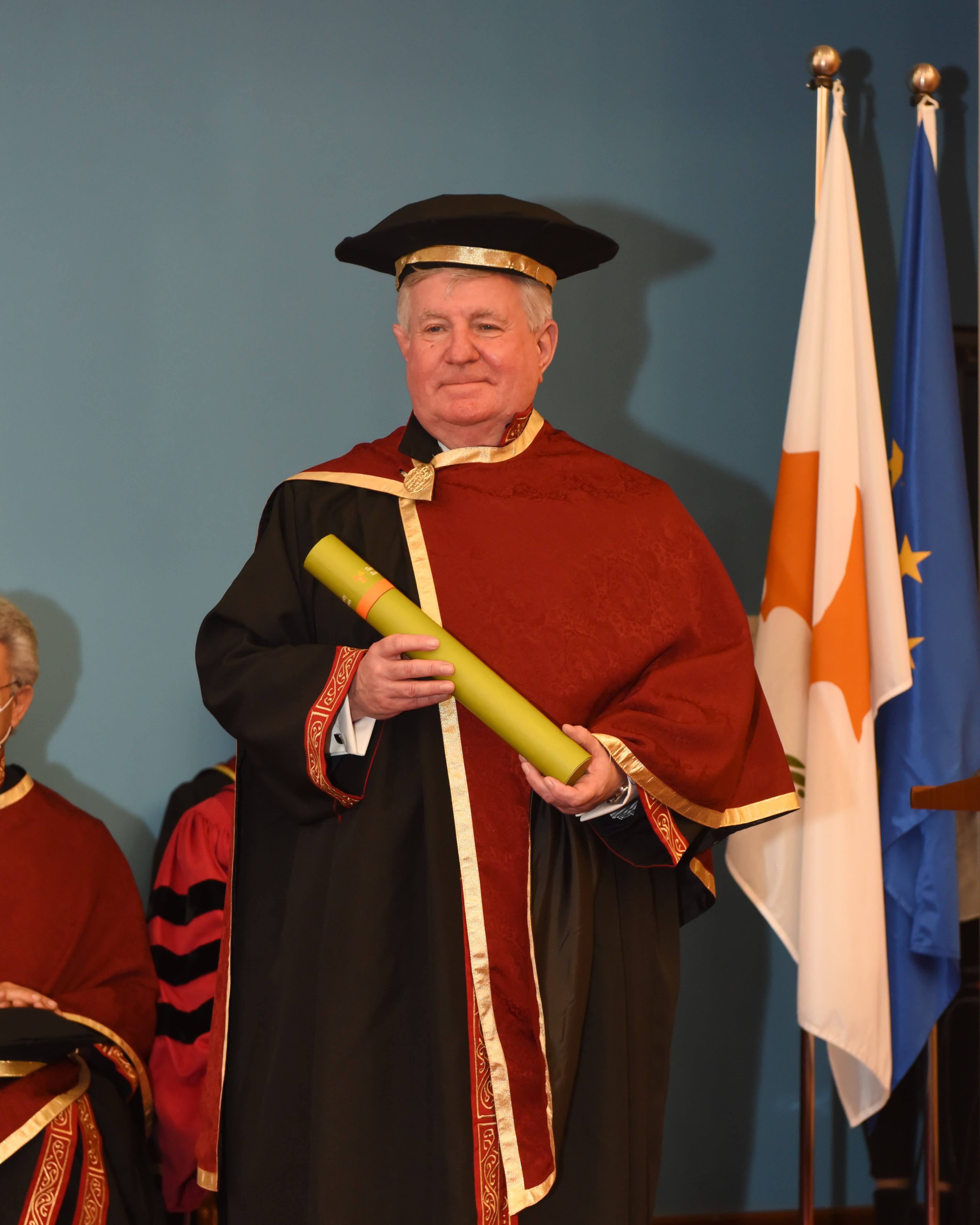 Man in red robe holding degree