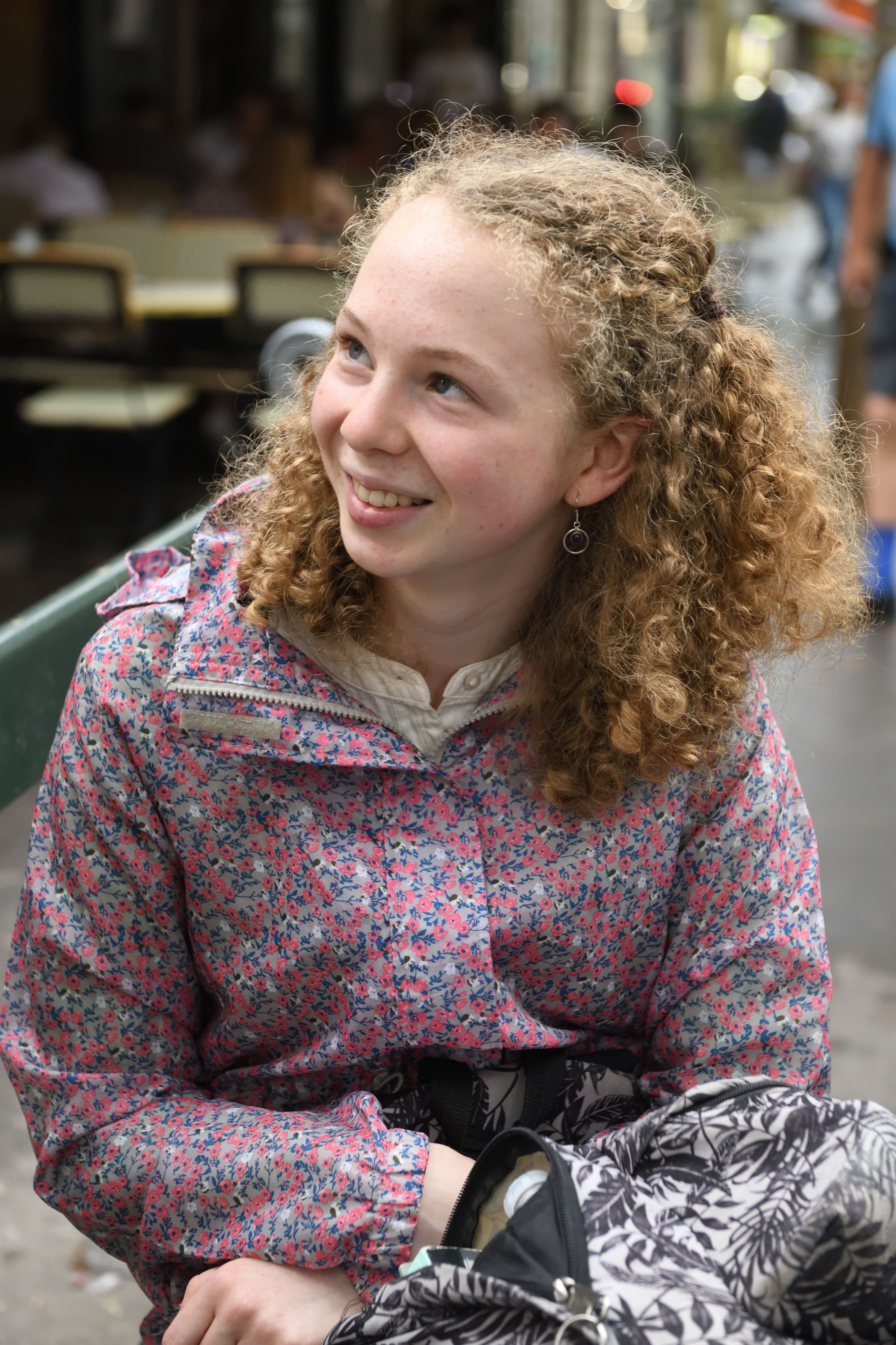 Girl with red curly hair in a pink floral jacket