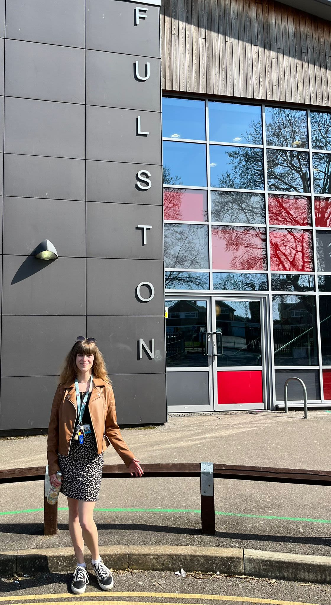 Woman standing outside a school with a big grey sign