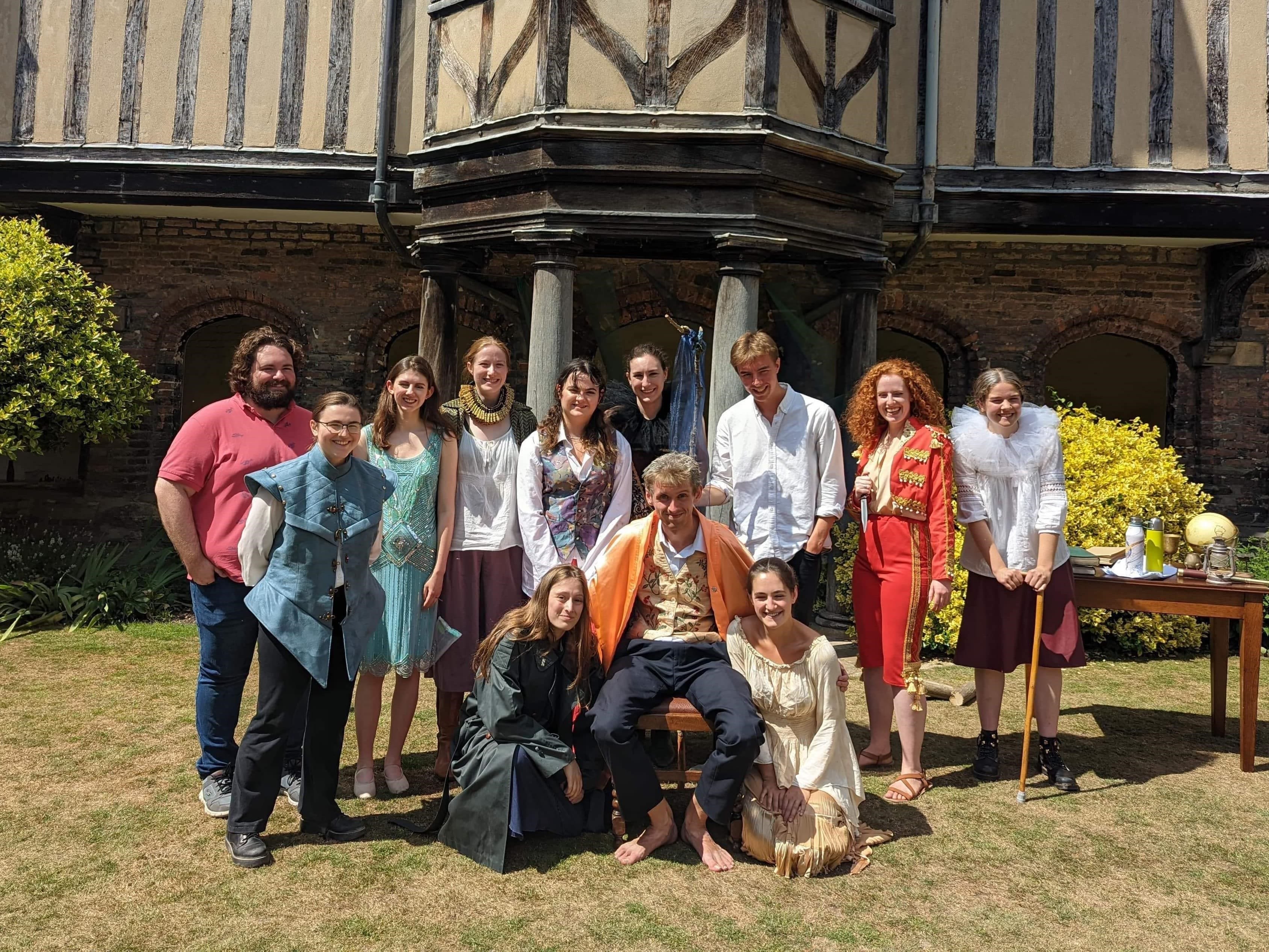 A group of people dressed Shakespearean in front of a medieval building
