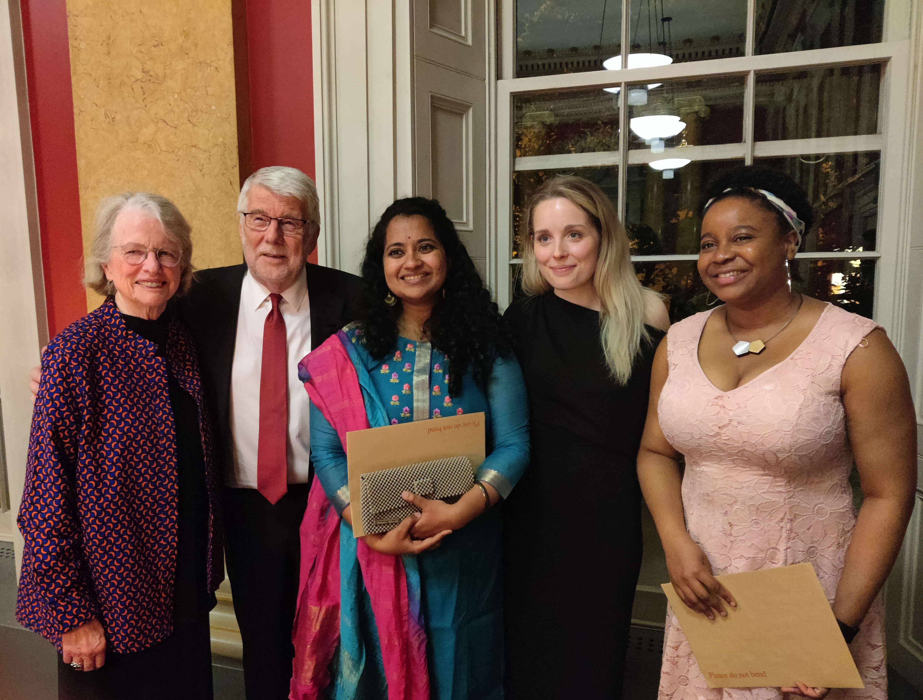 A woman in a sari in the middle of two young women and an elderly couple