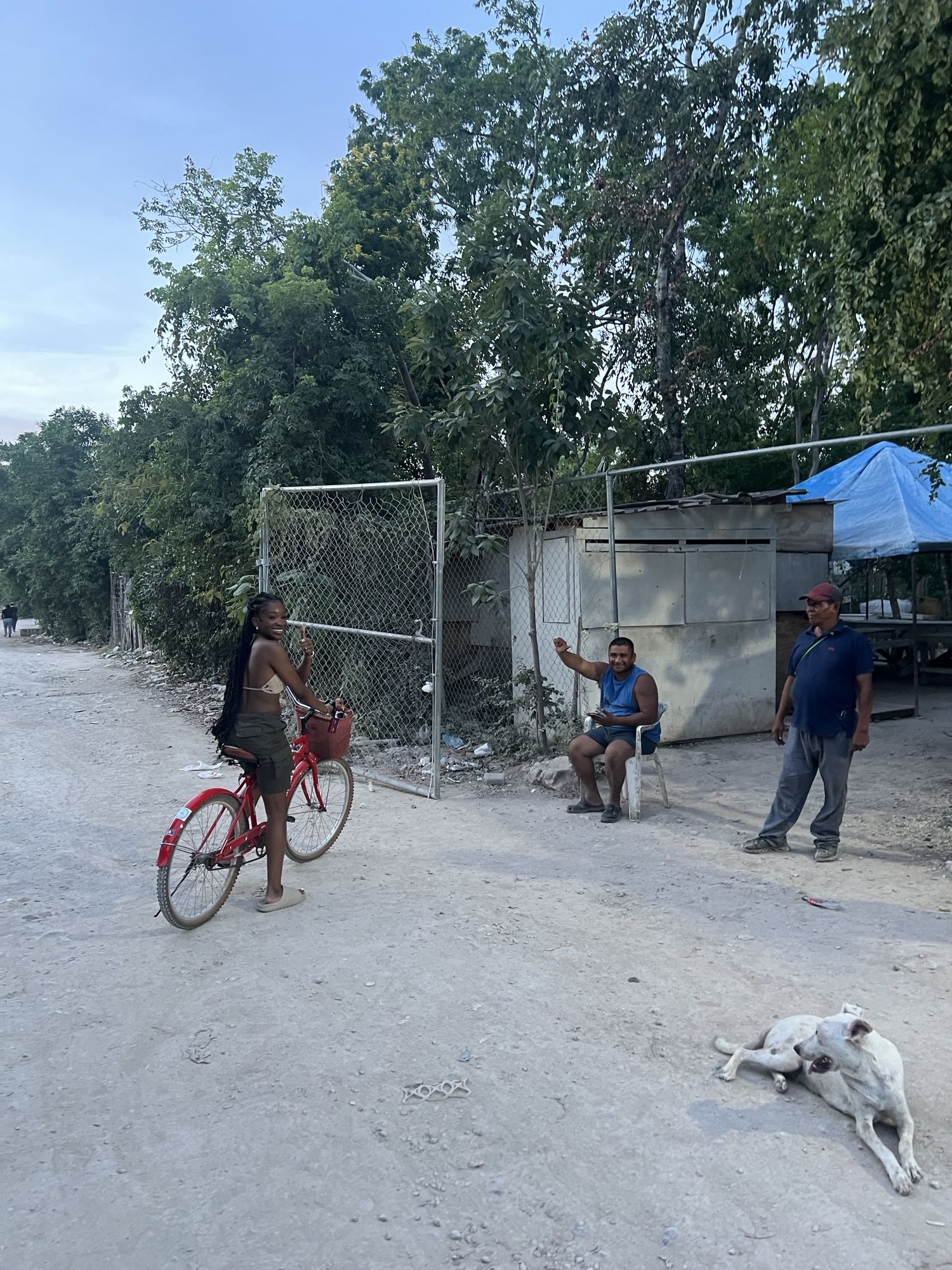 A girl on a bike with two men waving at the camera