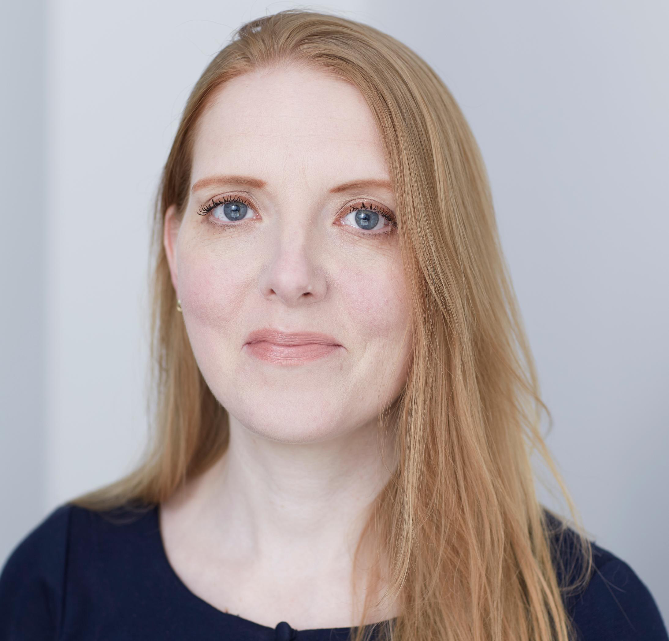 A woman with brown hair and blue eyes looking at the camera
